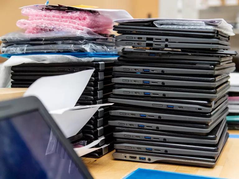 Dozens of laptops stacked on a desk