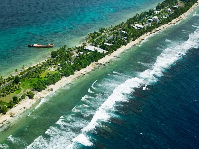 An aerial view of Funafuti atoll on Tuvalu, with a vast ocean surrounding a thin strip of land