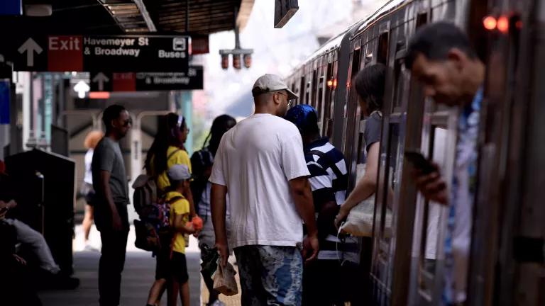 People enter a train on the platform at the Marcy Av subway station