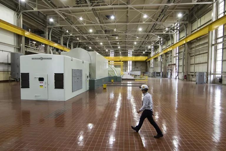 A man in a hardhat walks in a large industrial building