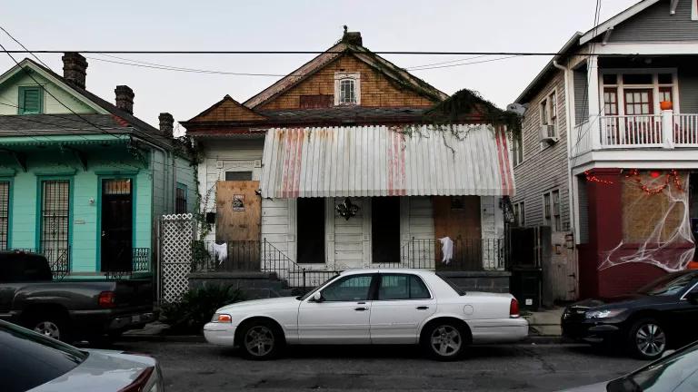 A home on a city block with doors and windows boarded up