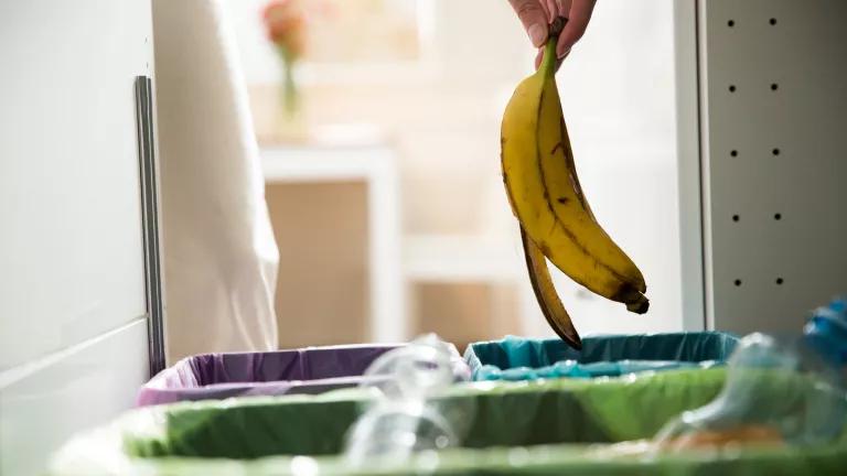 Banana peel being dropped into compost bin