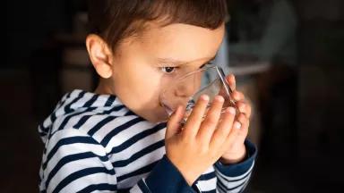 A young boy drinking from a glass of water