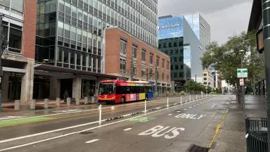 A red bus driving through an empty city street