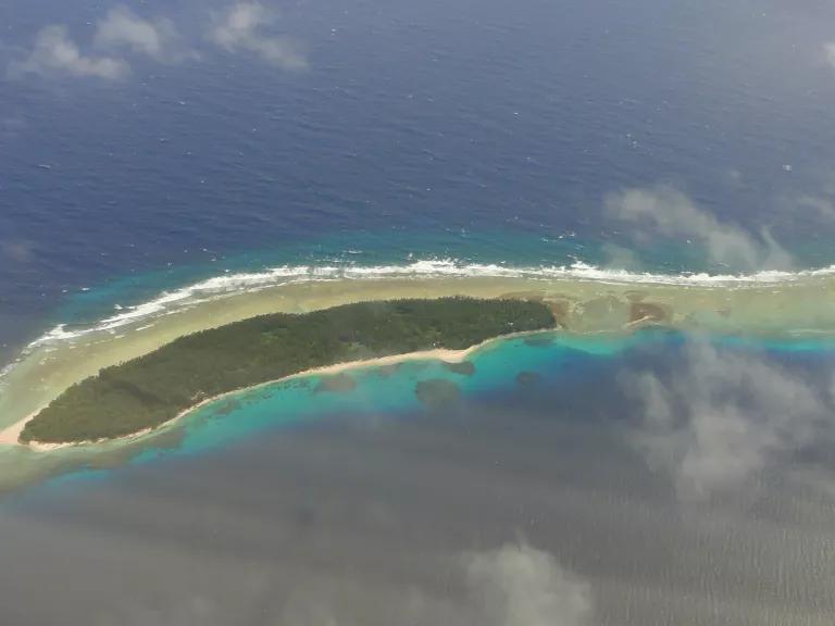 An aerial vew of an island surrounded by ocean, with turquoise water near the shoreline