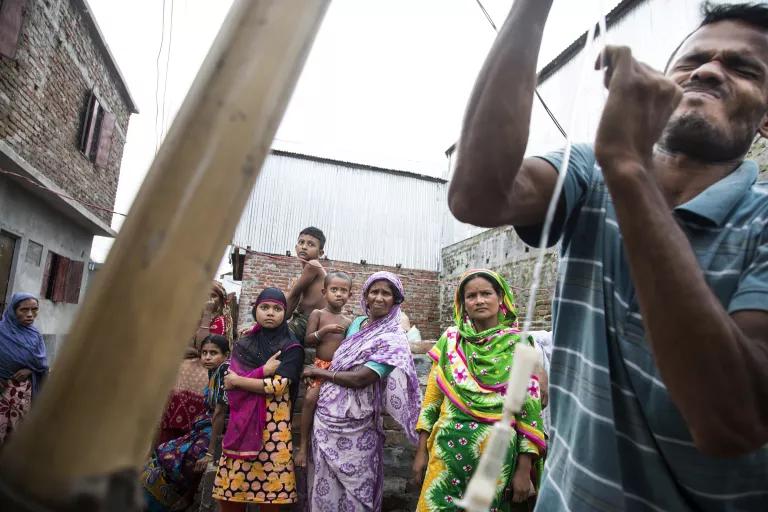 A man pulls on a rope while other people look on from behind him