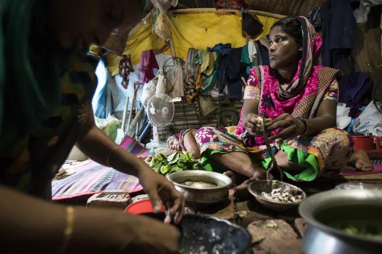 Two women sit on the floor preparing food