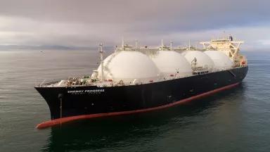 A ship with four large white domes moves through open water