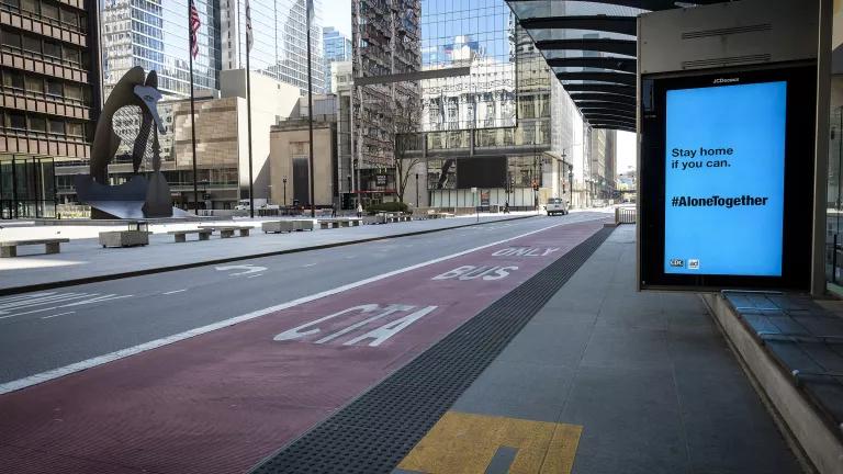 A bus stop on the side of an empty multi-lane city street 