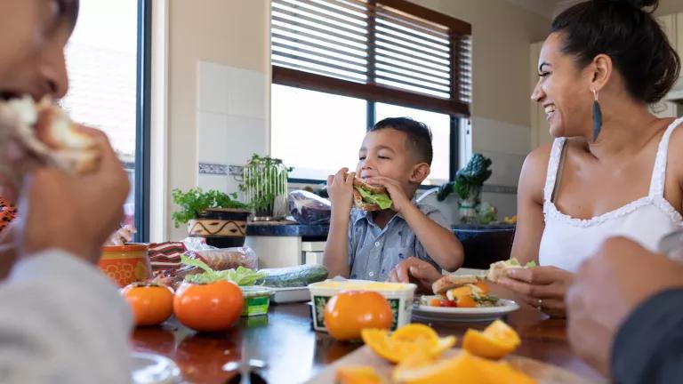 A Pacific Islander family eating lunch in their kitchen.