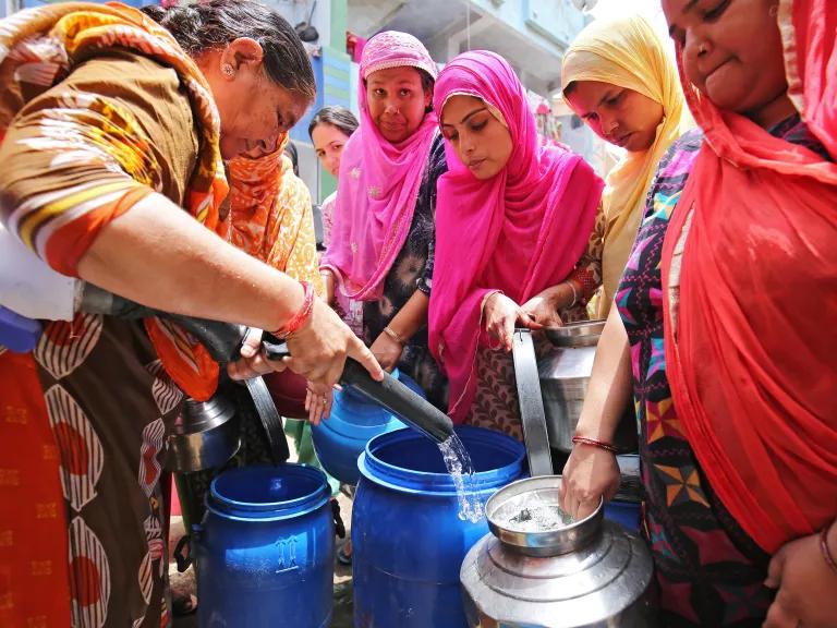 Residents filling their empty containers with water from a municipal corporation tanker on a hot day in the outskirts of Ahmedabad, India