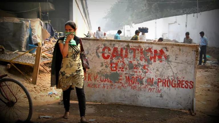 A woman walks on a city street while holding a cloth over her mouth and nose