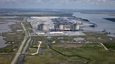 A liquified natural gas plant surrounded by water under hazy skies