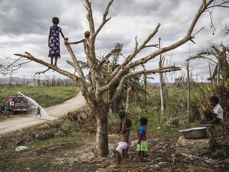 Children on Efate, the main island of Vanuatu, watch a water truck delivering supplies to their village.