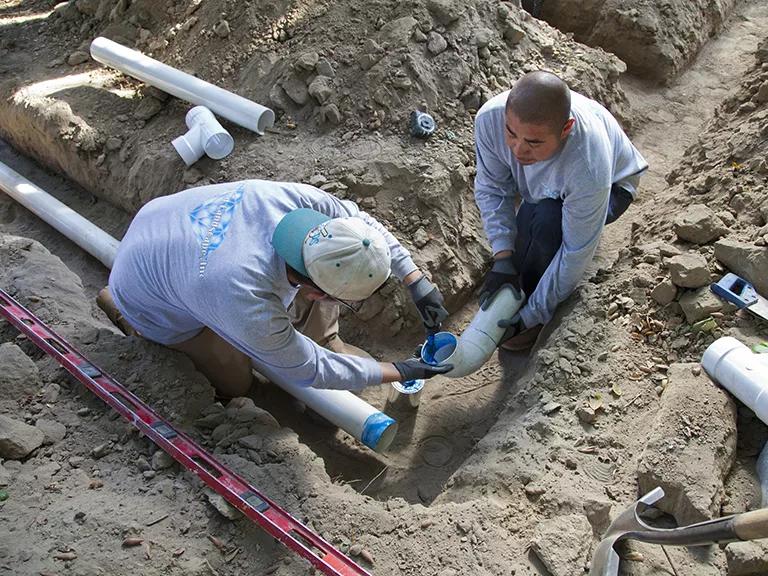 Workers install PVC pipes at a new home in Los Angeles, California, as part of a gravity-based rainwater harvesting system.