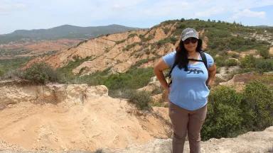 Elybeth Alcantar standing on a ridge with an expanse of rugged, dry terrain behind her