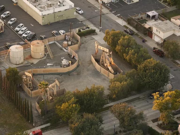 An aerial view of oil pumpjacks and storage tanks in a residential neighborhood of Wilmington, Los Angeles, California, on February 16, 2022