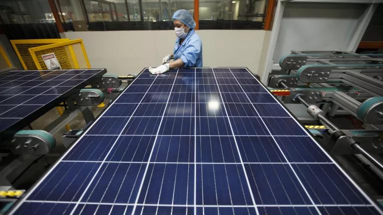 A person wearing white gloves wipes down the surface of a solar panel