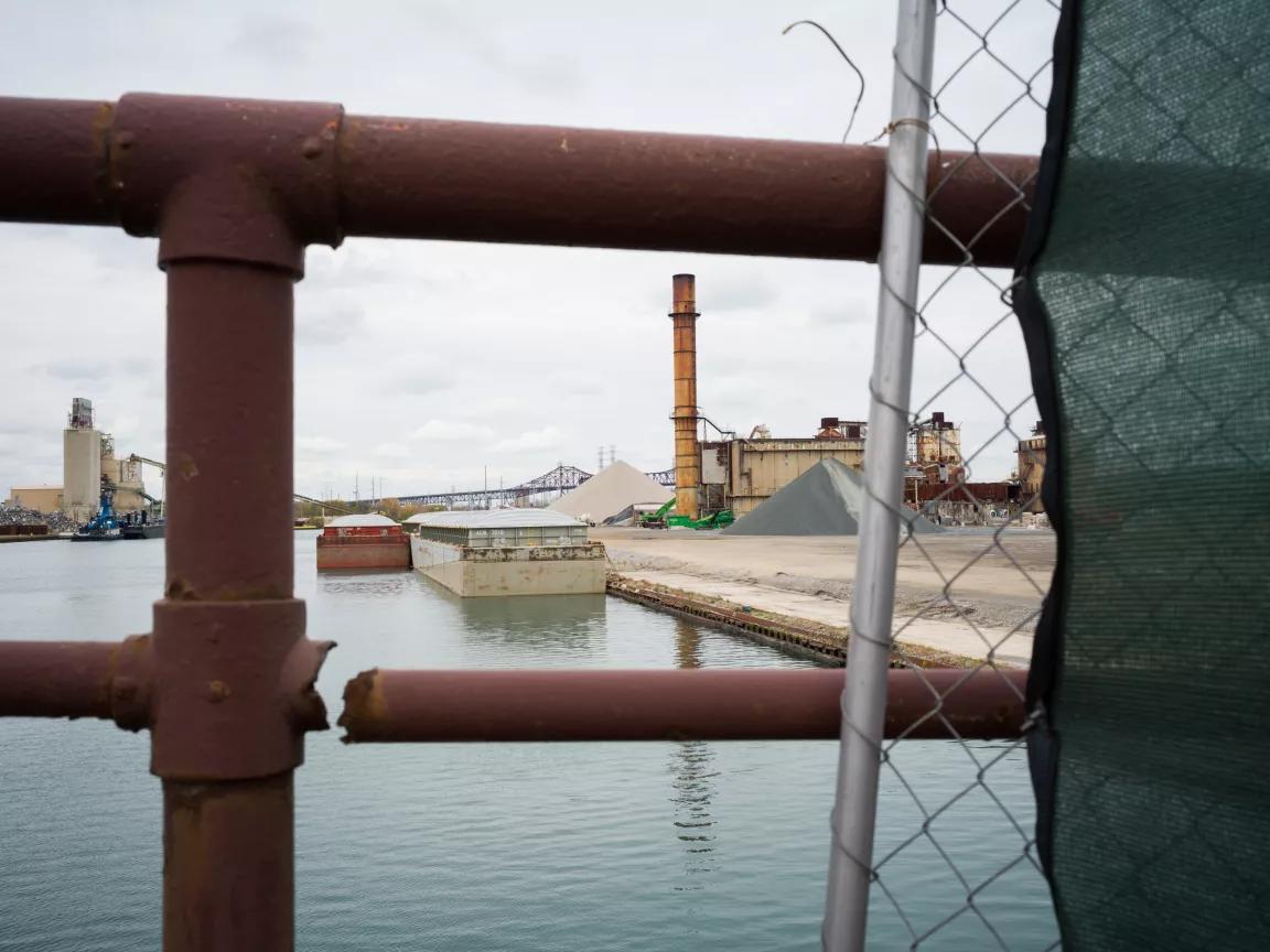 A view through a bronze metal railing of an industrial site near a body of water in the South Side of Chicago