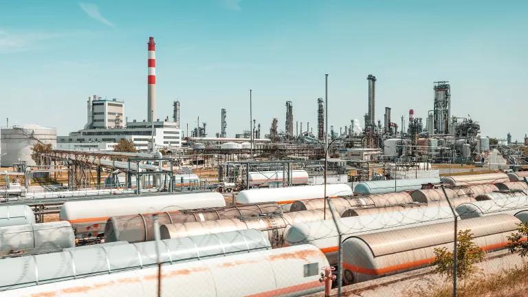 Large tanks lined up next to a refining facility