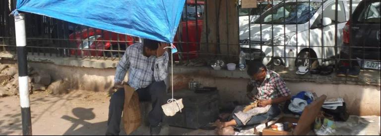 A man in Ahmedabad, Gujarat has his hand to his head as he works under a makeshift shelter to escape the heat