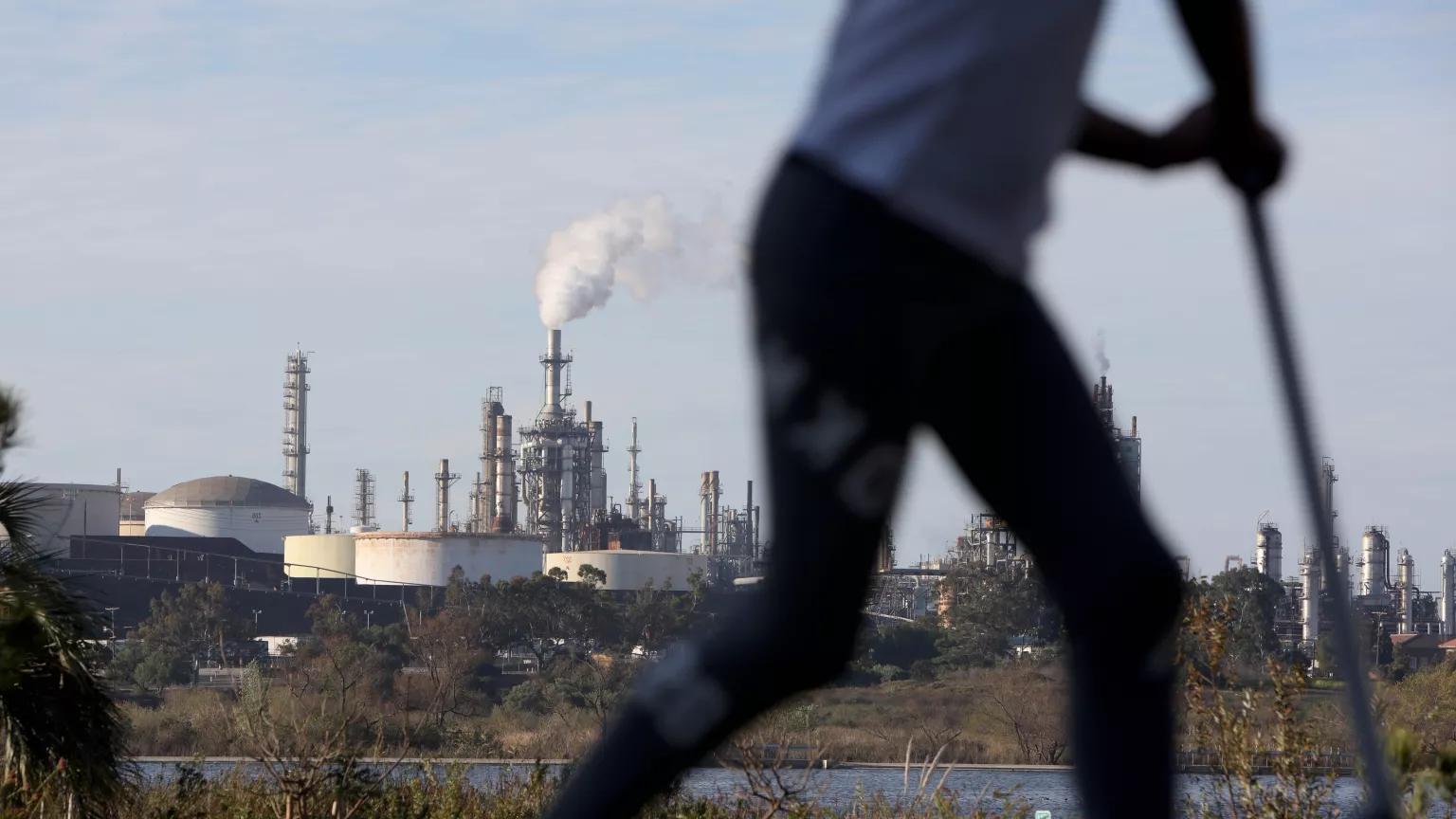 A child rides a scooter in Ken Malloy Harbor Regional Park, with a Rio Tinto refinery in the background