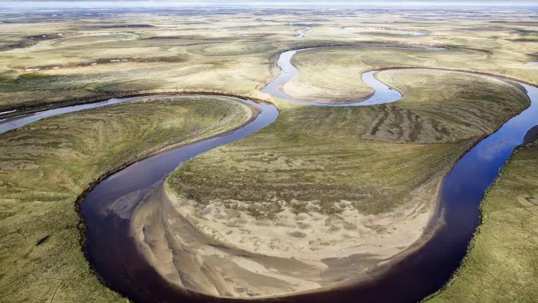 A narrow river snakes through a flat expanse of land