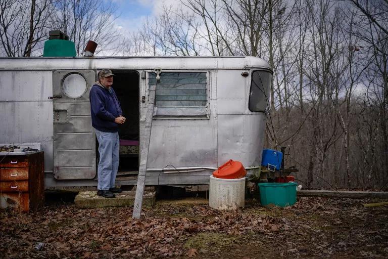 A man stands at the door of a mobile home