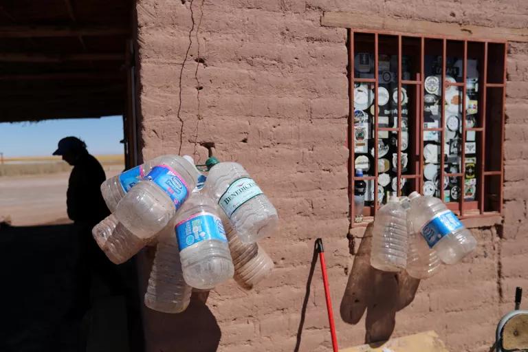 Plastic jugs hang from hooks on a the exterior of a brown building