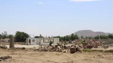 A torn-down house with rubble surrounding it in a desolate field