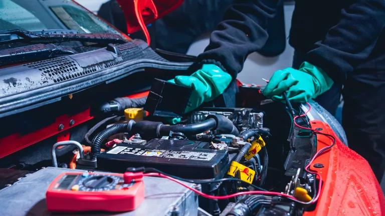 A mechanic servicing the battery compartment of an electric car.