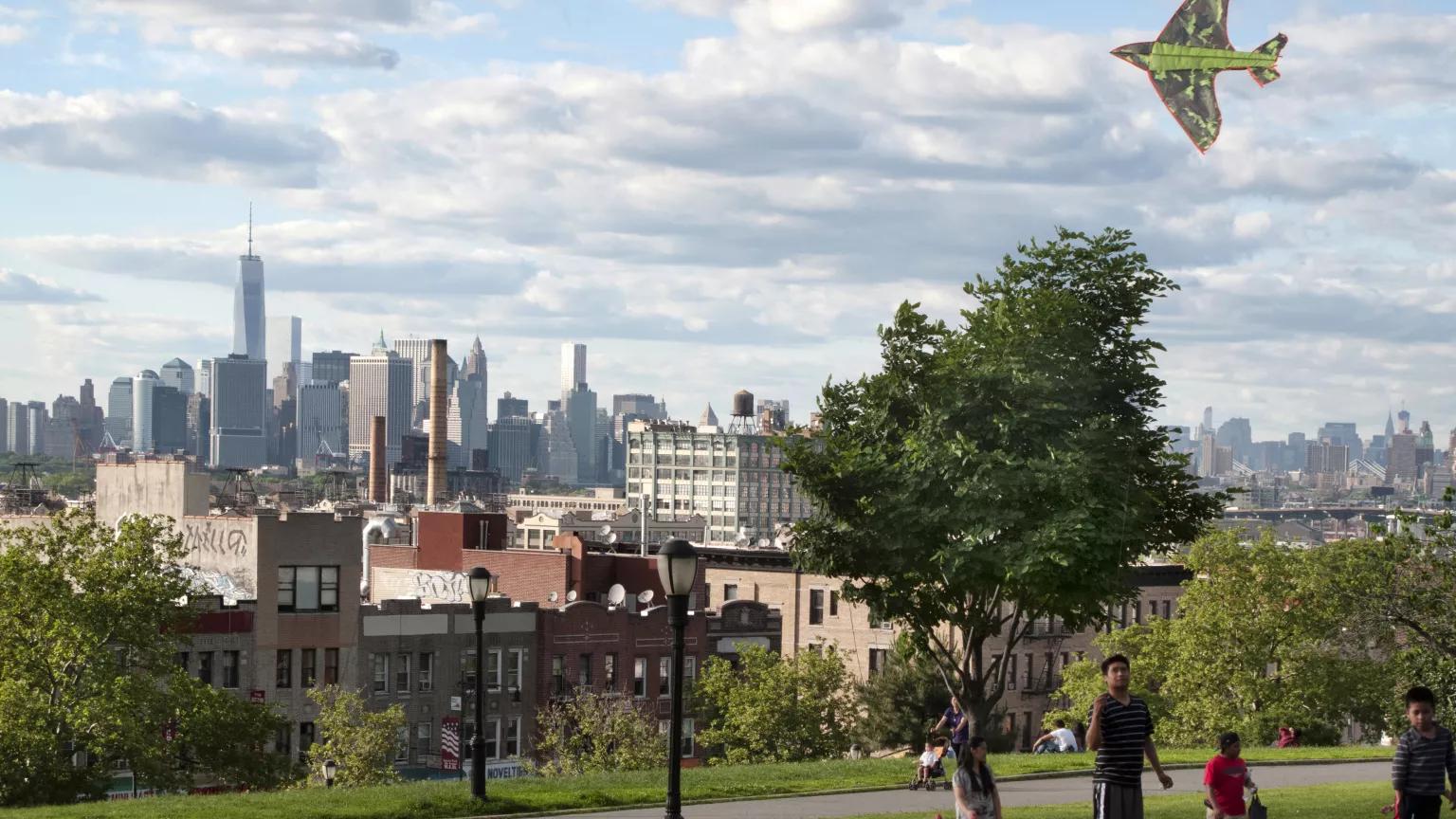 A family playing in Sunset Park, Brooklyn, with a view of Manhattan in the background