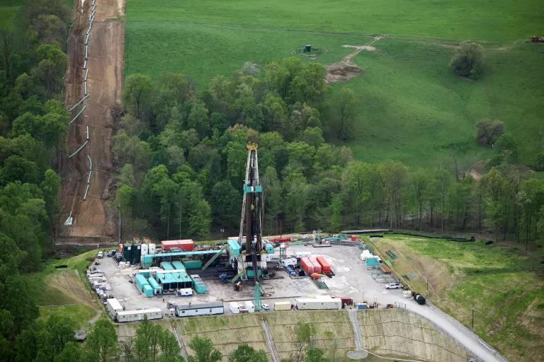 A rig and large pipeline on a clearing near clusters of trees