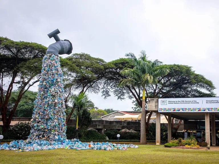 A 30-foot-tall art installation of a faucet suspended in air and pouring plastic bottles instead of water